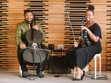 two string performers sitting in chair